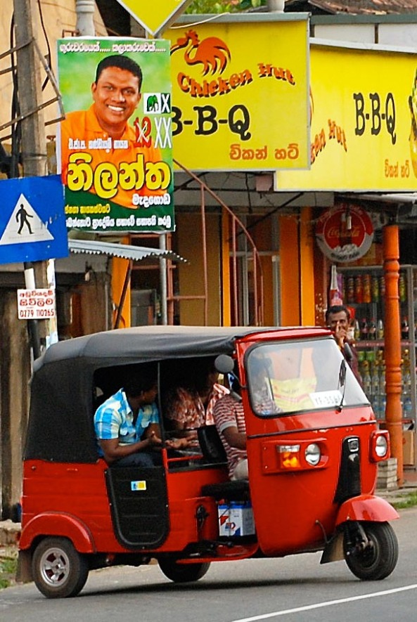 A bright red tuk-tuk on Srilankan roads