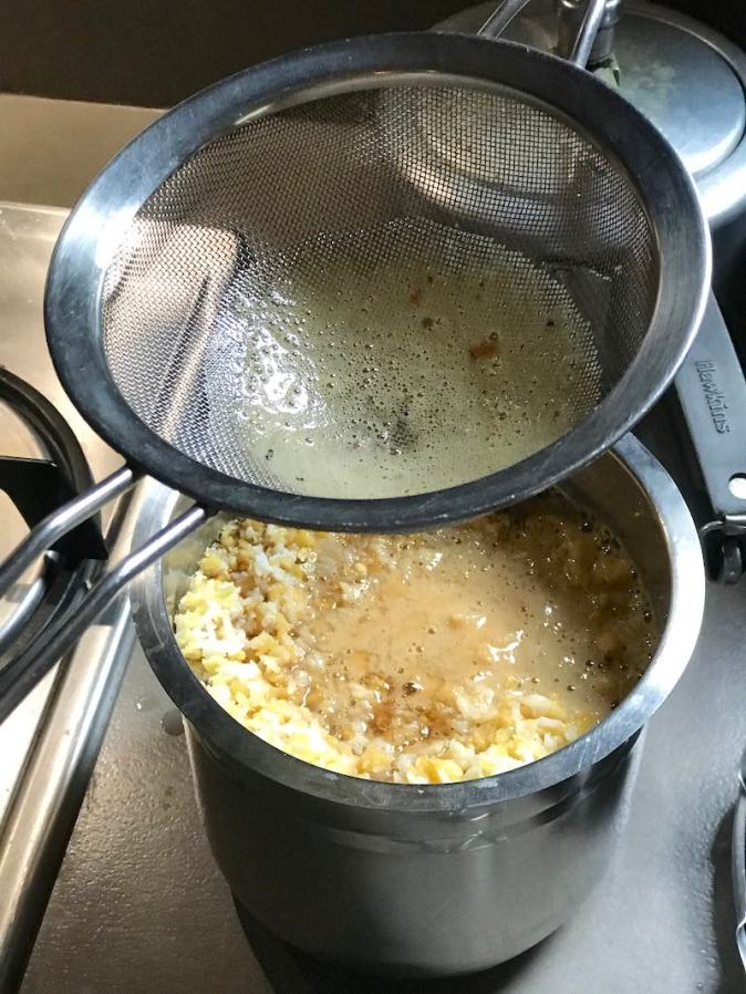 Filtering the jaggery through a sieve before mixing it in Sakkarai Pongal